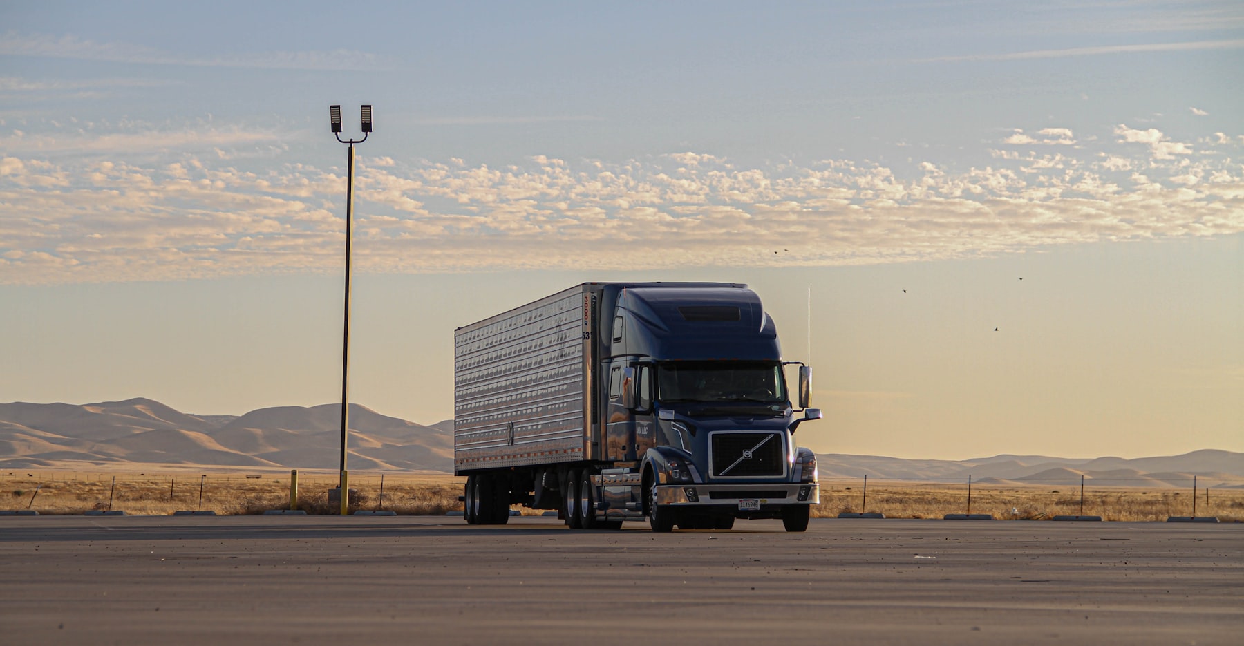 Sleeper semi truck parked at a yard at sunrise